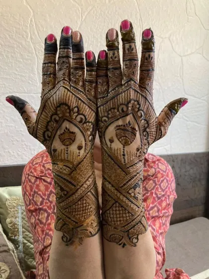 A stunning full-hand design with criss-cross patterns and hanging bell motifs, held up proudly by the client.
