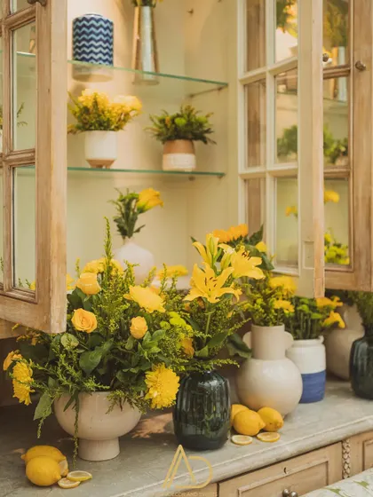 A close-up of the Haldi decor, with beautiful yellow flowers and fresh lemons artfully arranged inside a vintage-style wooden cabinet.