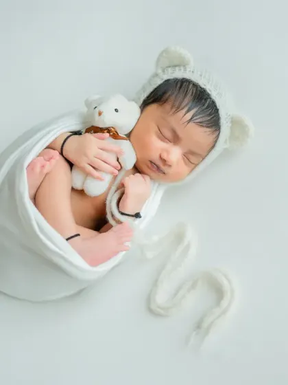 This full-body shot shows the classic 'potato sack' wrap, which keeps the baby snug and secure while showing off their tiny feet.