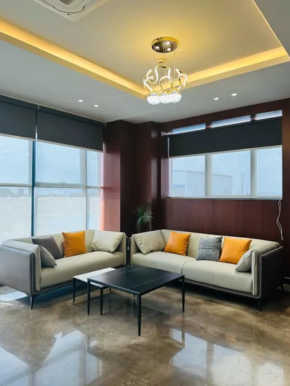 This executive waiting lounge is surrounded by large windows fitted with roller blinds, allowing for control over privacy and natural light. The polished floor reflects the light, making the space feel bright and expansive.