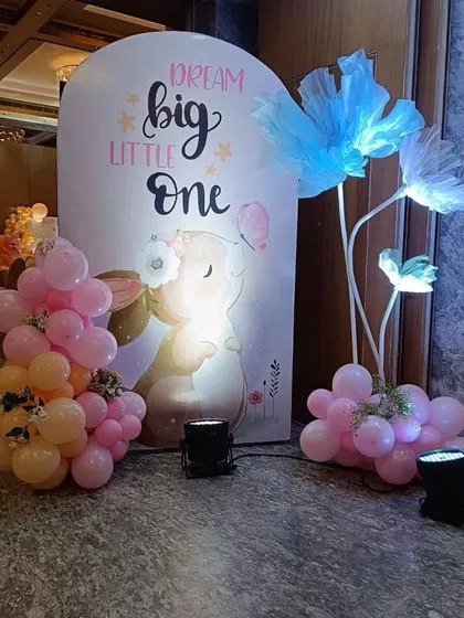 A "Dream Big Little One" backdrop from the bunny-themed party, featuring an adorable illustration and illuminated flower props.