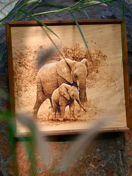 A pyrography portrait of a mother and baby elephant. This wood burn art is a touching depiction of wildlife, created with skillful heat application to bring out the texture and emotion of the scene.