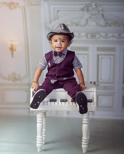 Piano keys and cheeky grins. This little gentleman, dressed in a vest and fedora, is sitting up proudly on the piano, a perfect portrait for a 6-9 month old.