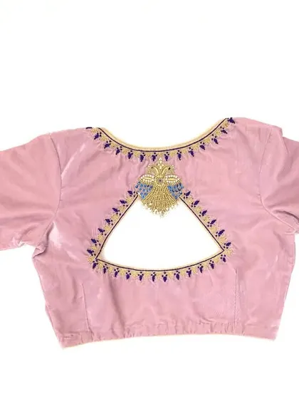A unique triangular cut-out back on a pink velvet blouse, with delicate blue and gold embroidery.
