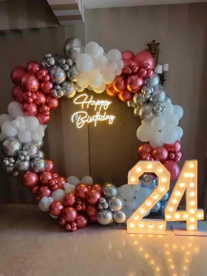 A 24th birthday celebration with a red, white, and silver balloon ring and large light-up numbers.