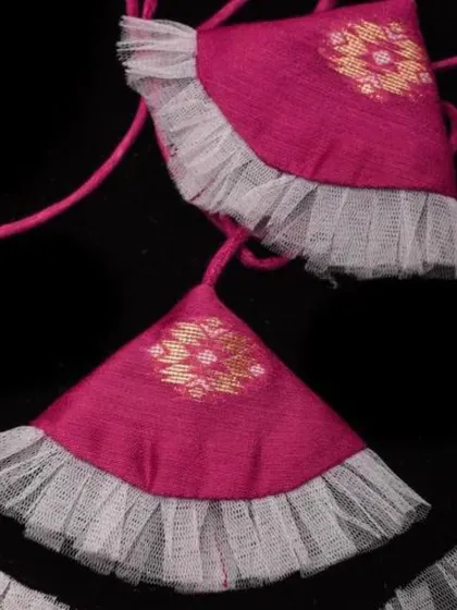 The beautiful fabric tassels on our pink Jamdani cotton blouse, featuring a ruffled net detail.