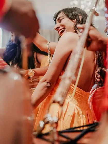 The bride dancing with joy, surrounded by the energetic beats of dhol players during her Sangeet.