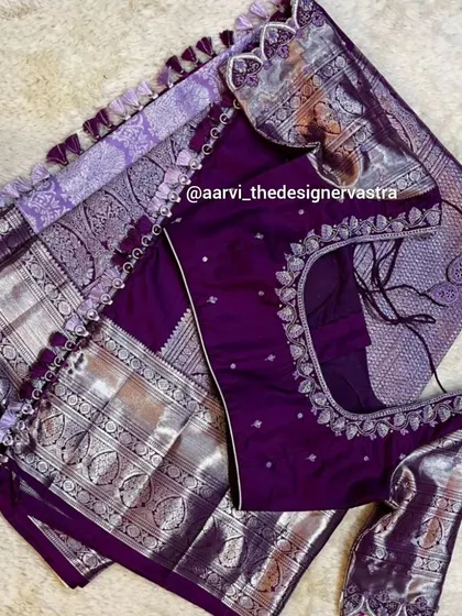 A top down view of the purple blouse and saree, highlighting the intricate embroidery and the beautiful silver zari work.