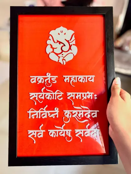 Holding the Ganesha shloka frame to show its size. It's a substantial piece that makes a wonderful gift for housewarmings.