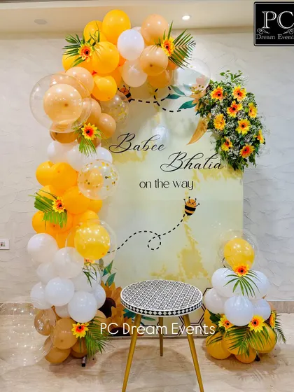 A "Sweet as can Bee" themed baby shower decoration. This setup features a cheerful yellow and white balloon arch, sunflower accents, and a custom backdrop for the mom-to-be.