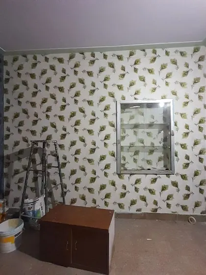 A room featuring two different wallpapers. One wall has a peacock feather pattern, while the accent wall uses a bold damask design, creating a unique and eclectic look.