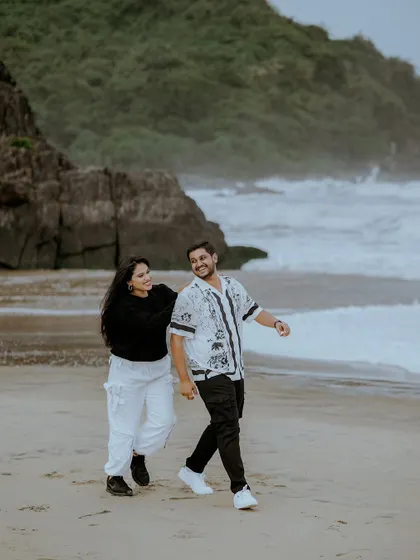 A candid, joyful moment captured as the couple walks along the beach, their relaxed outfits perfect for the coastal pre-wedding vibe.