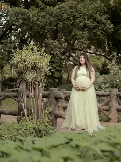 A serene outdoor portrait in a light green gown, capturing a peaceful moment in a lush park.