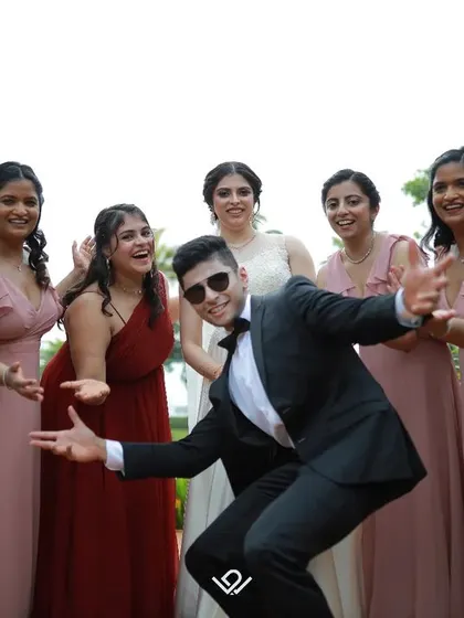 The groom joins the bridesmaids for a fun, energetic photo, adding a touch of humor and personality to the wedding album.