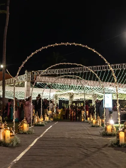 A magical night-time entrance created with a series of illuminated arches and a pathway lined with glowing lanterns and candles. This design creates a warm and inviting journey into the heart of the celebration.