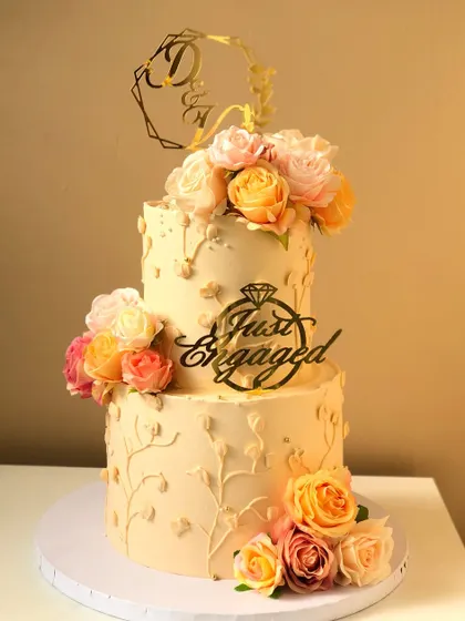 A two-tiered "Just Engaged" cake with a cascade of peach and pink roses.