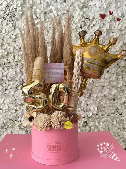 A 50th birthday bouquet box featuring dried florals, gold number balloons, and a crown, perfect for a last-minute surprise.