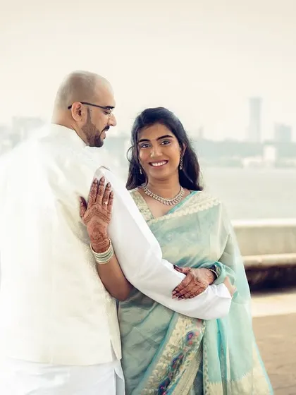 A candid pre-wedding shot with the Mumbai skyline in the background, capturing a natural moment of connection between the couple.