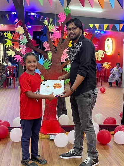 Presenting a certificate of appreciation to a young performer. She worked so hard on her routines for the showcase.