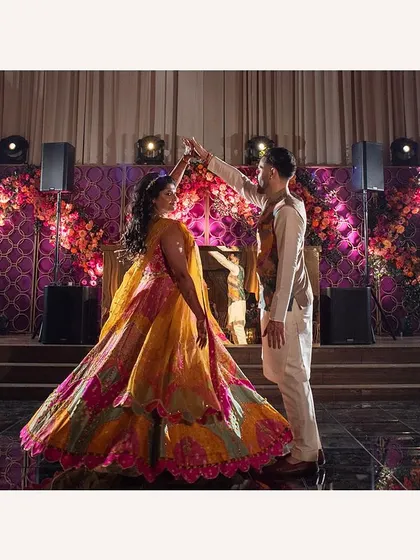 The couple shares a dance at their Sangeet. The twirl of her multi-colored lehenga creates a beautiful cascade of festive hues.