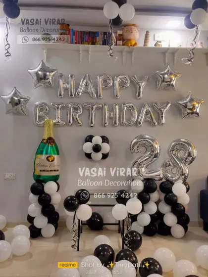 A classic and elegant setup for a 28th birthday. We used black, white, and silver balloons with star accents and a large champagne bottle foil balloon to create a sophisticated party corner.