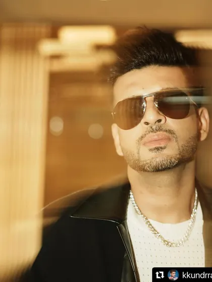 A close-up portrait of Karan Kundrra. The combination of the textured shirt, chain, and sunglasses creates a look that is both relaxed and sophisticated.