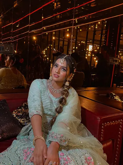 A relaxed and elegant seated pose. The mirrored background reflects the ambient lighting, creating a warm and inviting atmosphere that enhances the overall look.