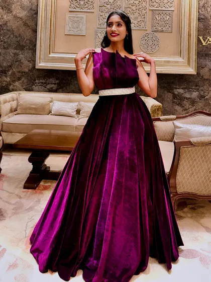 A full-length shot showcasing the beautiful fall and rich texture of the magenta velvet gown in a luxurious indoor setting.