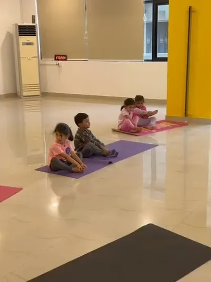 A group of children sits on their mats, practicing stretches. The calm and organized atmosphere of our indoor classes is ideal for focused activities like gymnastics.