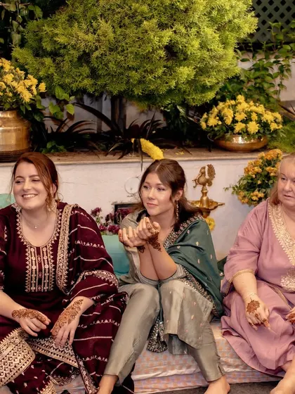 Guests from abroad enjoying the Mehendi ceremony, their hands adorned with henna, fully embracing the Indian cultural experience.