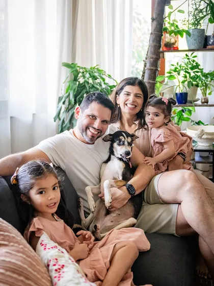 A beautiful family portrait on the couch with two young daughters and their sweet rescue dog, Choco.