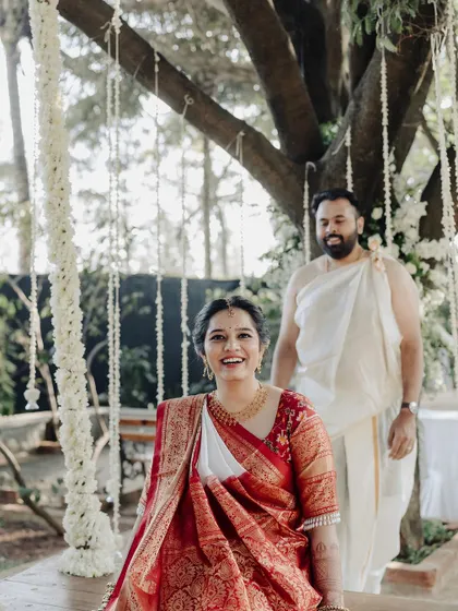 The bride's joyful expression as the groom approaches from behind. This candid style portrait, set in a beautiful garden, captures a moment of happy anticipation.
