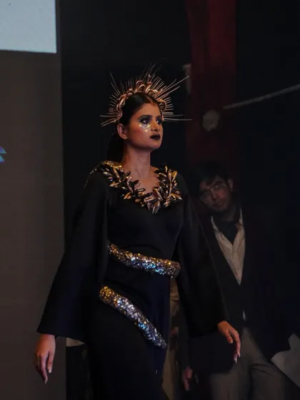 A model walks the runway in a dramatic black dress with a sparkling snake embellishment.