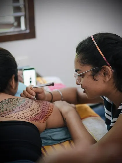 A behind the scenes shot of me applying a colorful mermaid scale pattern on the model's back. This shows the versatility of colored henna for creating imaginative and large scale body art.