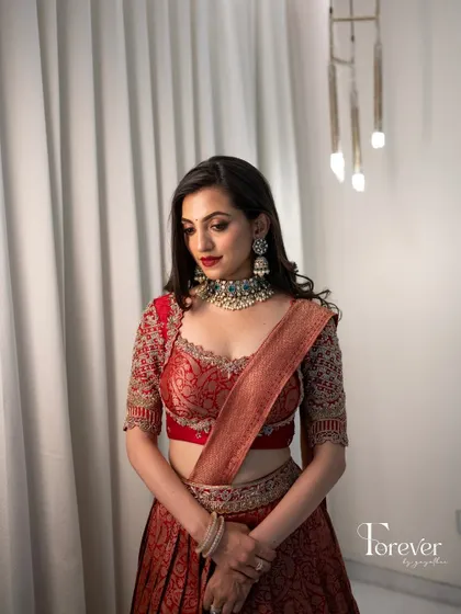 A full-length shot of this modern red lehenga look, showing the elegant silhouette and the way the makeup ties the whole look together.