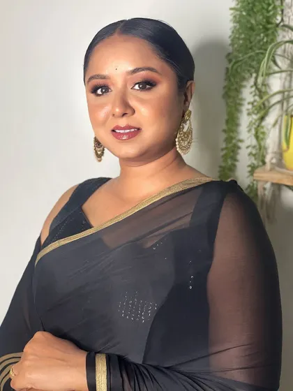 This look is simple yet elegant. The clean makeup and neat hairstyle allow the client's natural beauty to shine through, complemented by the classic black saree.