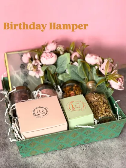 This birthday hamper in a rustic green tray is bursting with color and flavor. It's packed with granola, assorted nuts, and our signature cookie boxes, all adorned with a beautiful floral arrangement.