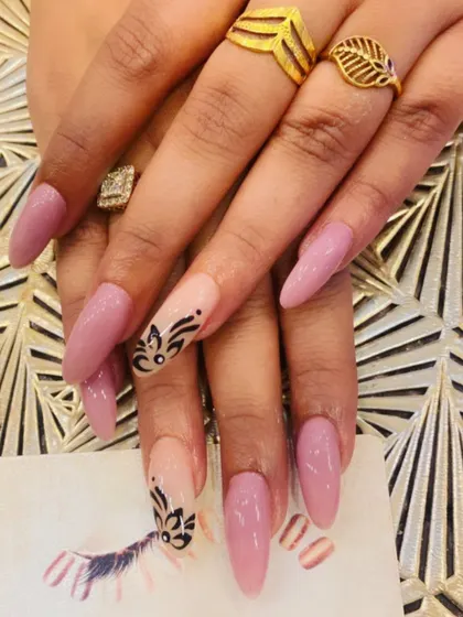 A long, elegant stiletto set in a soft mauve color. The ring fingers are accented with a sheer base and intricate, hand-painted black floral patterns.