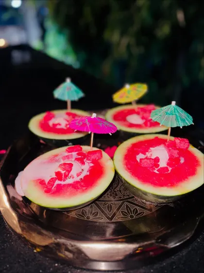 A creative presentation of watermelon ice cream, served in hollowed-out watermelon shells and topped with cocktail umbrellas.