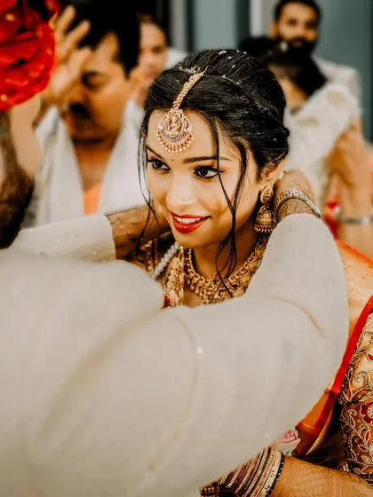 A close-up of a sacred moment in a South Indian wedding, as the groom performs a ritual for his bride. The focus on her expressive eyes and his gentle hands tells a story of love and tradition.