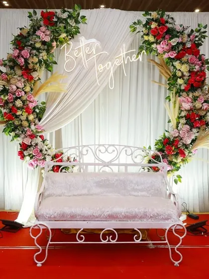 This elegant anniversary stage combines a floral ring backdrop with custom neon signage and classic seating. We focus on creating a picture perfect focal point for your celebration, ensuring every photo captures the magic of the moment.