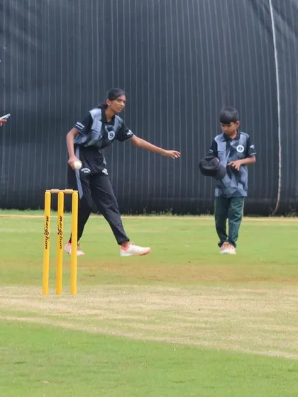 A young bowler practices her run-up and delivery, focusing on rhythm and technique during a training session.