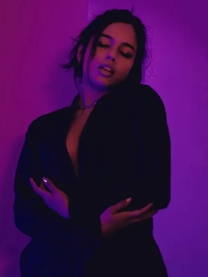 Drenched in purple and pink light, this portrait is moody, sensual, and full of emotion.