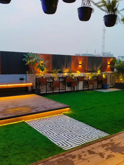 A wide view of the Uttam Nagar terrace, showing the different levels of decking and the lush artificial lawn.