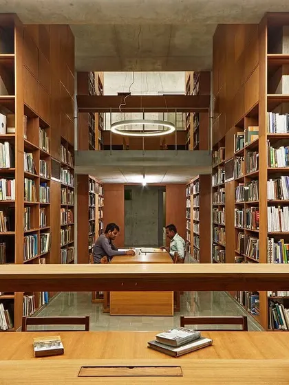 We design libraries as sanctuaries for knowledge and quiet contemplation. At the Lilavati Lalbhai Library at CEPT University, floor-to-ceiling wooden bookshelves create a warm, immersive environment, with carefully planned sightlines that draw the eye through the multi-level, subterranean space.