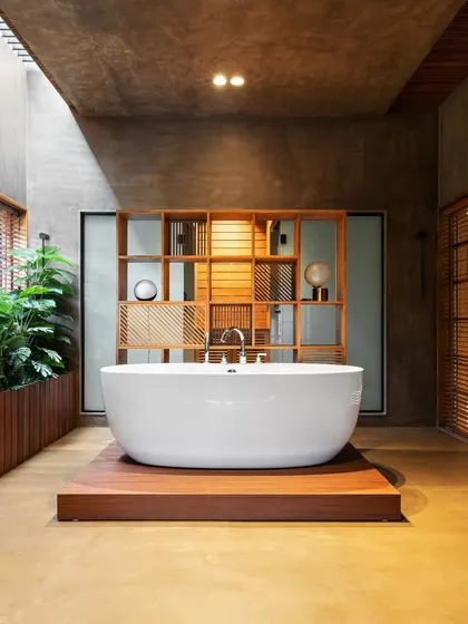 The master bathroom's freestanding tub, set in a spacious, light-filled room. Wooden shutters and an indoor planter bring elements of nature indoors, creating a true spa-like retreat.