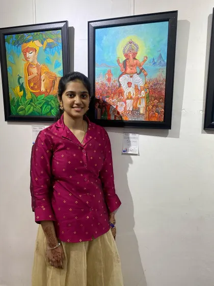 A student standing proudly next to her framed artwork at the CHITRAKAR exhibition.