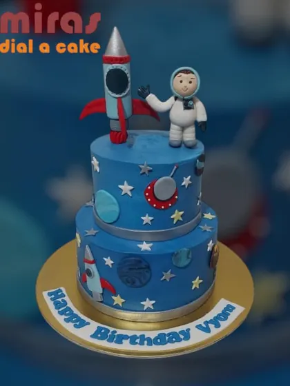 An out-of-this-world two-tier space adventure cake. This design features a brave astronaut, a rocket ship, and a galaxy of stars and planets, perfect for a little explorer's birthday blast-off.