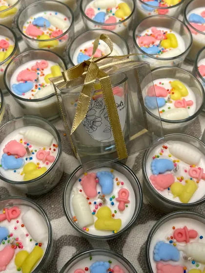 Here you can see one of the baby shower candles being packaged in a clear box with a gold ribbon. This presentation makes it a perfect, ready-to-give favor for guests.