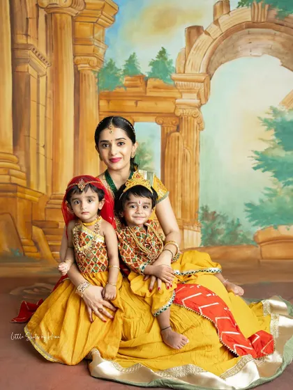 A loving family portrait featuring a mother with her two children in traditional Krishna costumes. It's a beautiful way to celebrate faith and family together.